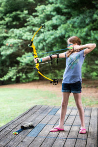 young girls aiming a bow and arrow