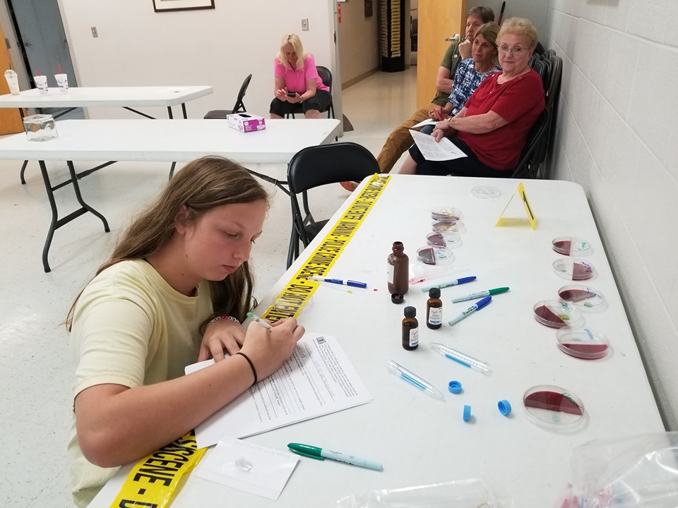 student at table examining crime scene equipment