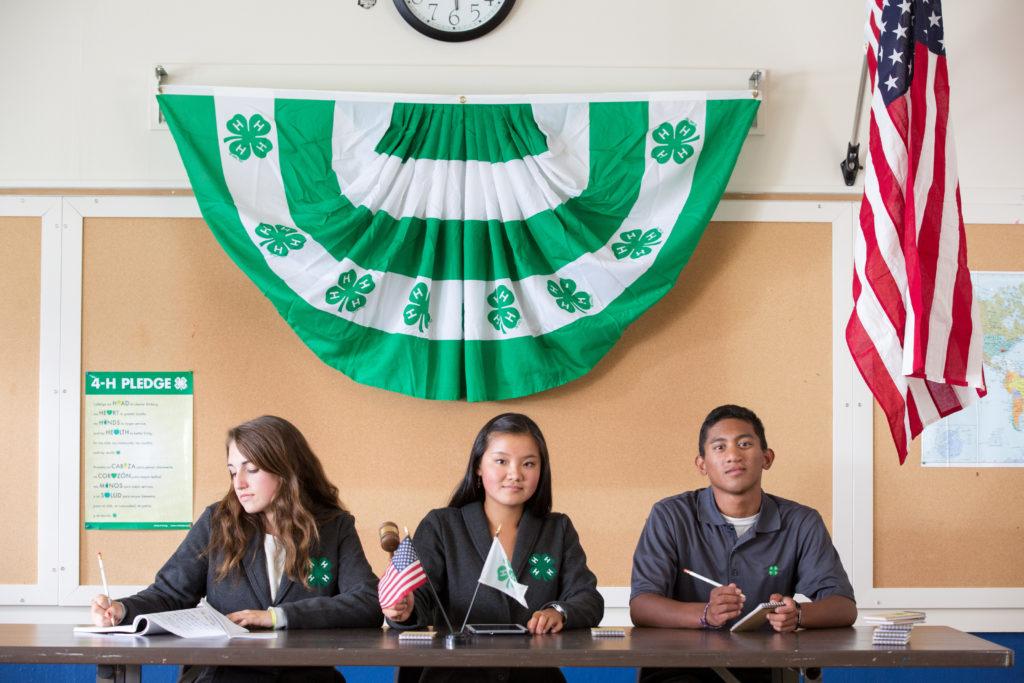Youth sitting at a table with 4-H Flag