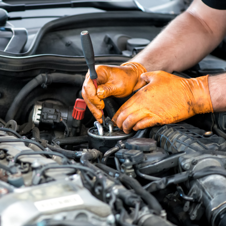 a man with orange gloves working on a car engine