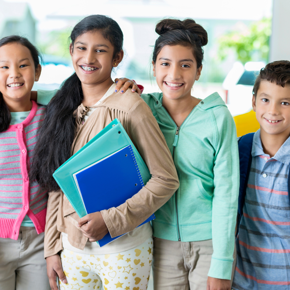 Many girls with braces smiling at the camera with notebooks in their arms